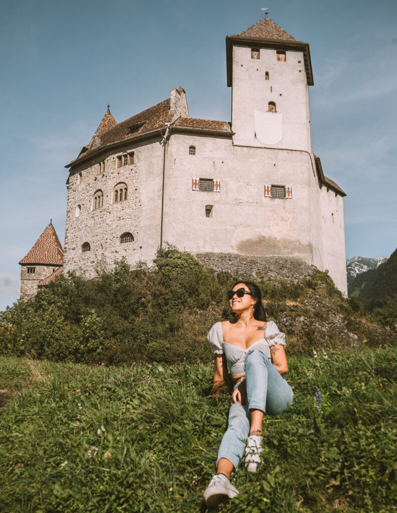 me sitting on the grass in front of a castle in Liechtenstein