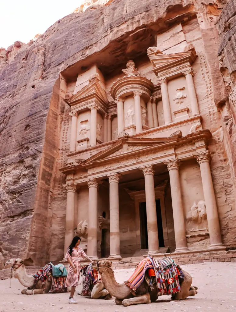 a girl with 3 camels in front of the treasury in petra in jordan 