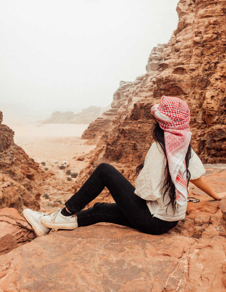 a girl looking at the view from a viewpoint over wadi rum in jordan