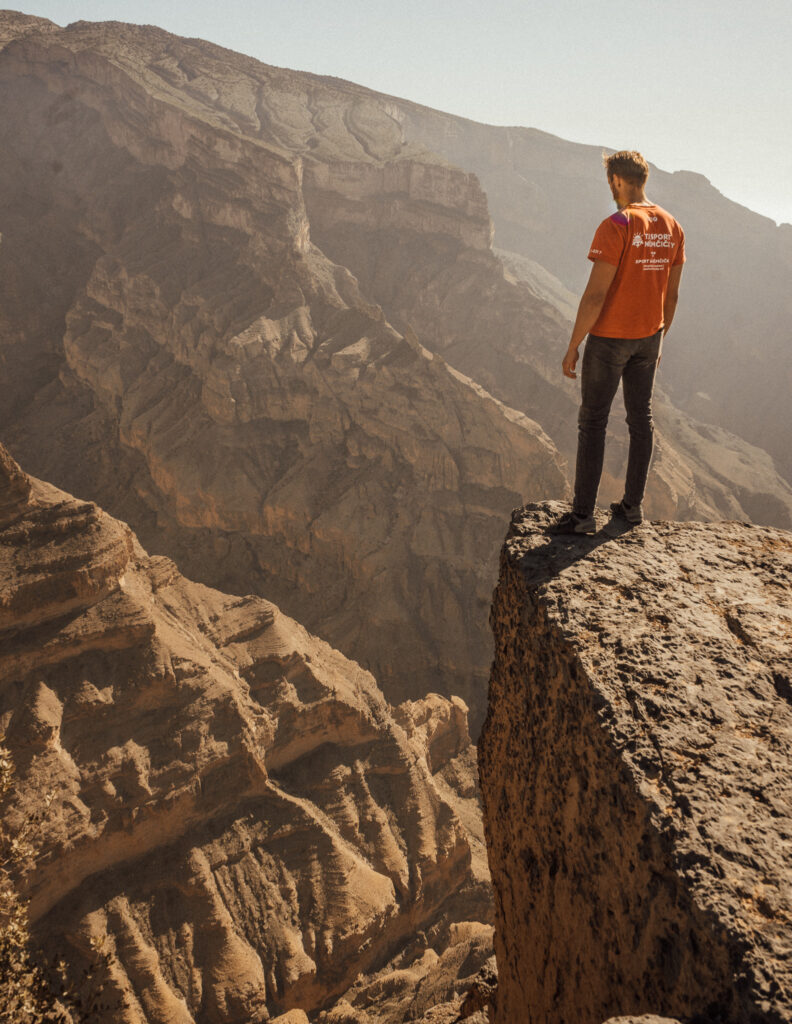 a man looking into a deep canyon at jebel shams in oman