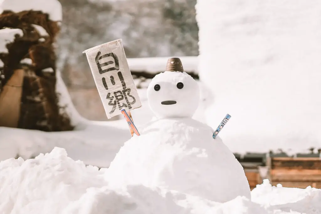 a snowman holding a japanese sign in shirakawa-go in winter in japan