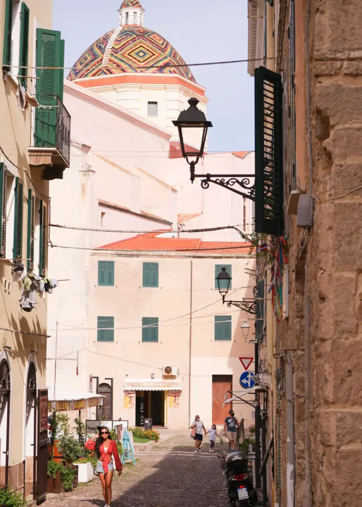 travel photos in Sardinia with a girl in front of a church with a colorful dome in Alghero