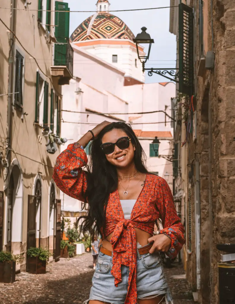 travel photos in Sardinia with a girl in front of a church with a colorful dome in Alghero