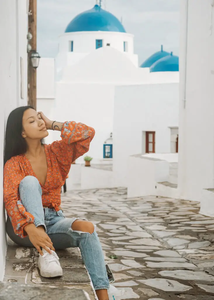 travel photos in Greece capturing a greek church with a blue dome and a girl