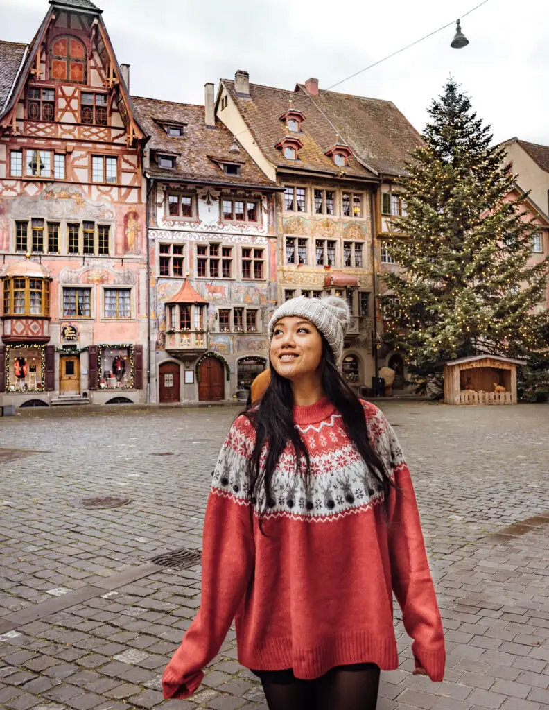 a girl in the town square at stein am rhein during christmas in front of a giant christmas tree