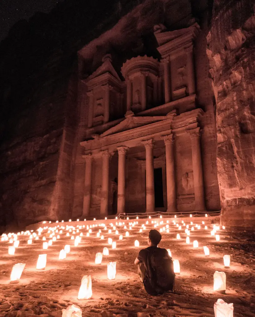 the treasury in petra at night with candles on the ground in front of it in jordan