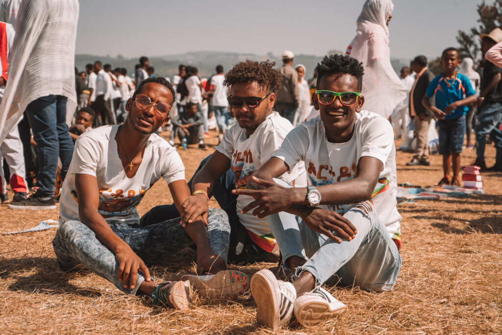 a group of men sitting in the grass celebrating timkat in addis ababa 