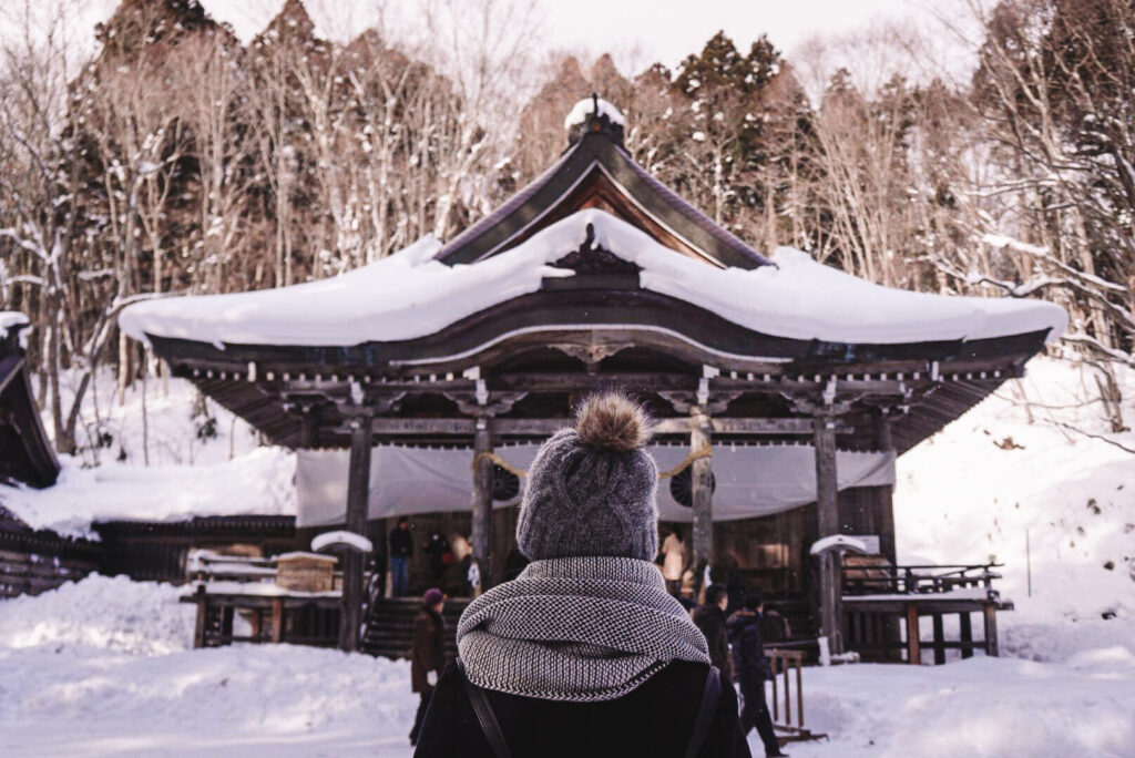 a girl standing in front of togakushi shrine in nagano prefecture of japan