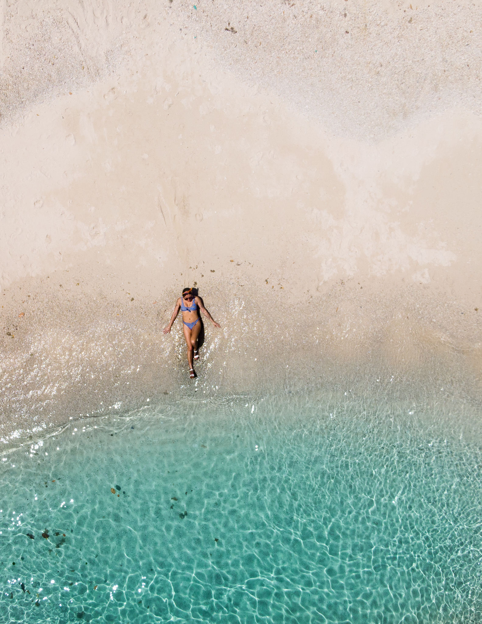 a girl on the beach laying in the white sand near clear blue water in donsol in the philippines