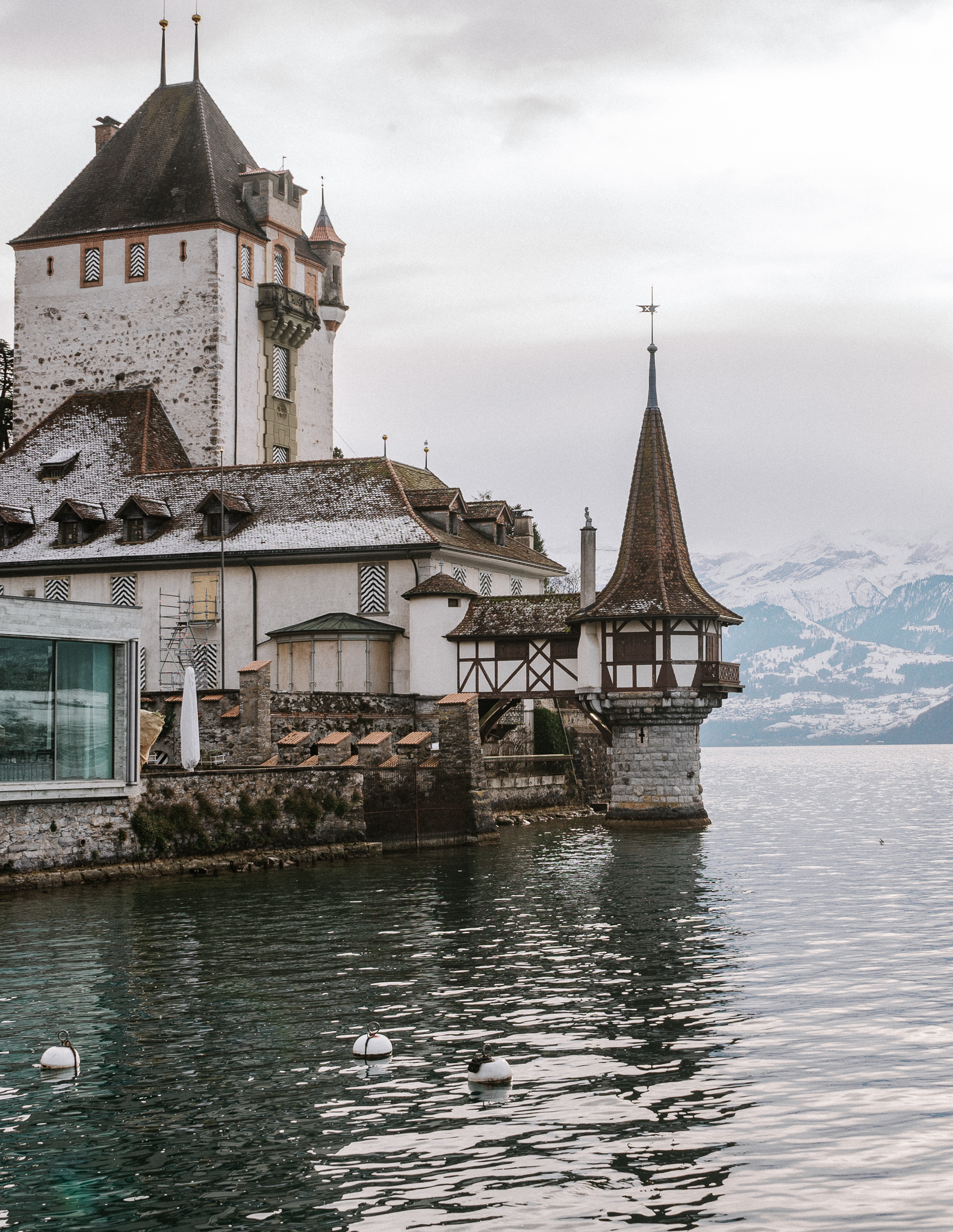 berhofen Castle and Thun lake in winter in Switzerland, with snowy mountains in the background