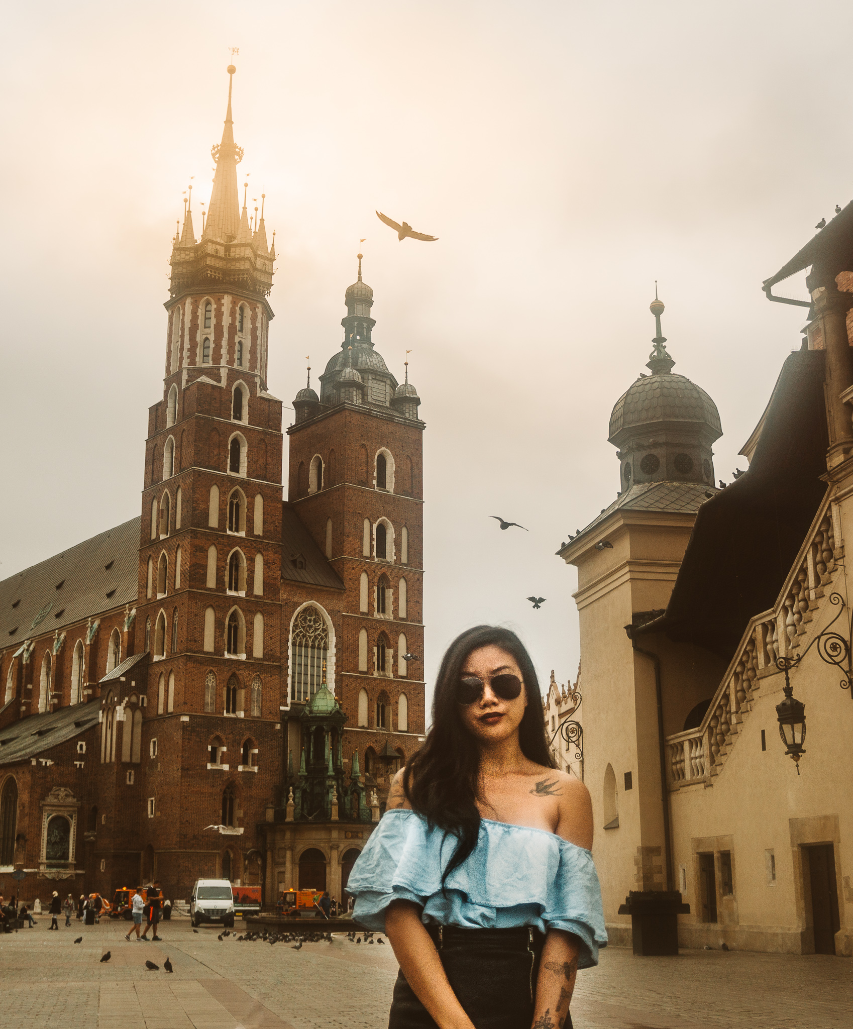 a girls in poland as a digital nomad in the city square of krakow with the church behind in poland