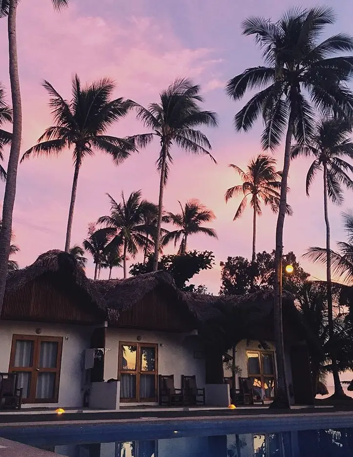 a pink sunset over three poolside bugalows at elysia hotel in donsol, in the Philippines