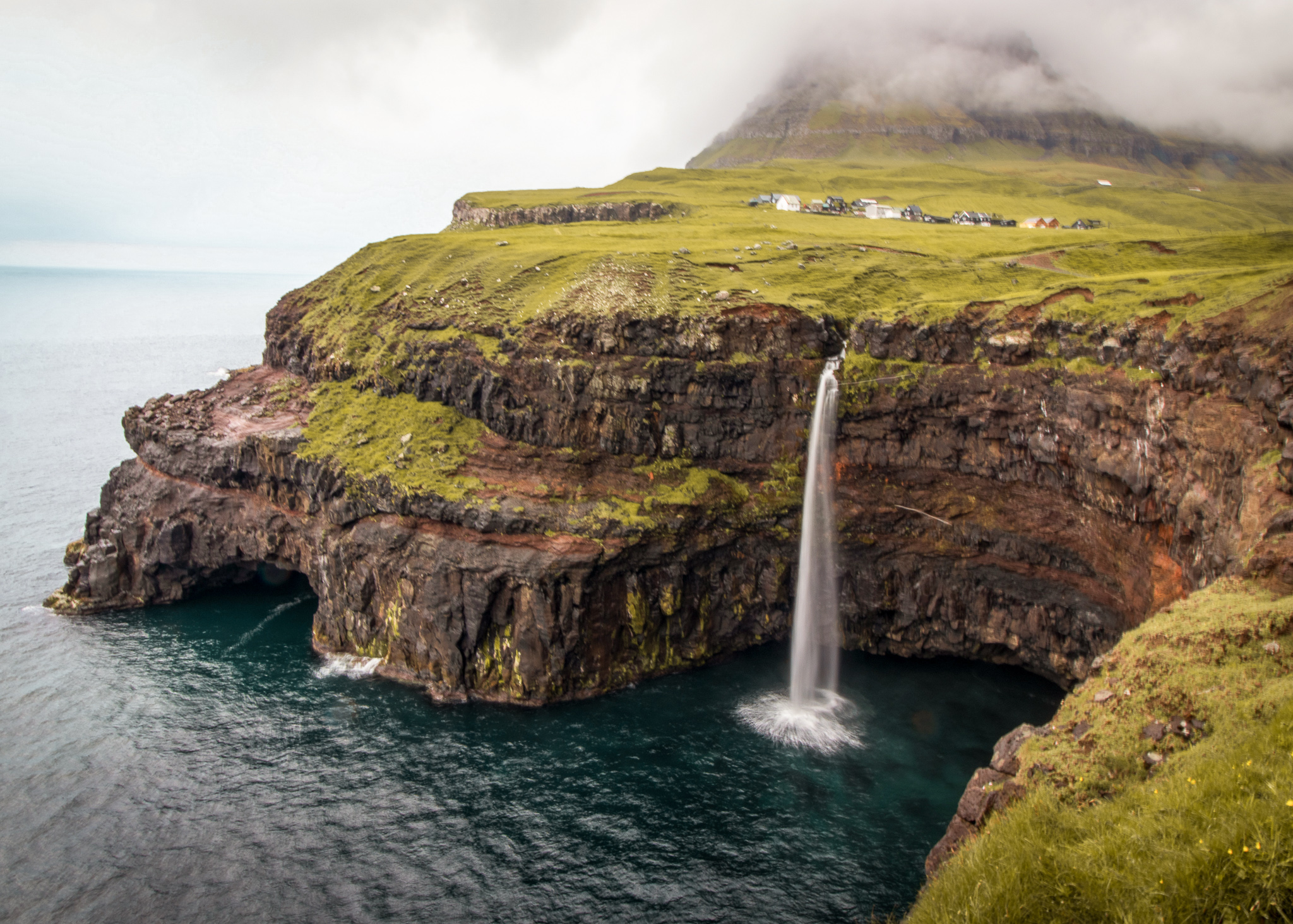 a waterfall on the faroe islands flowing directly into the sea off a cliff
