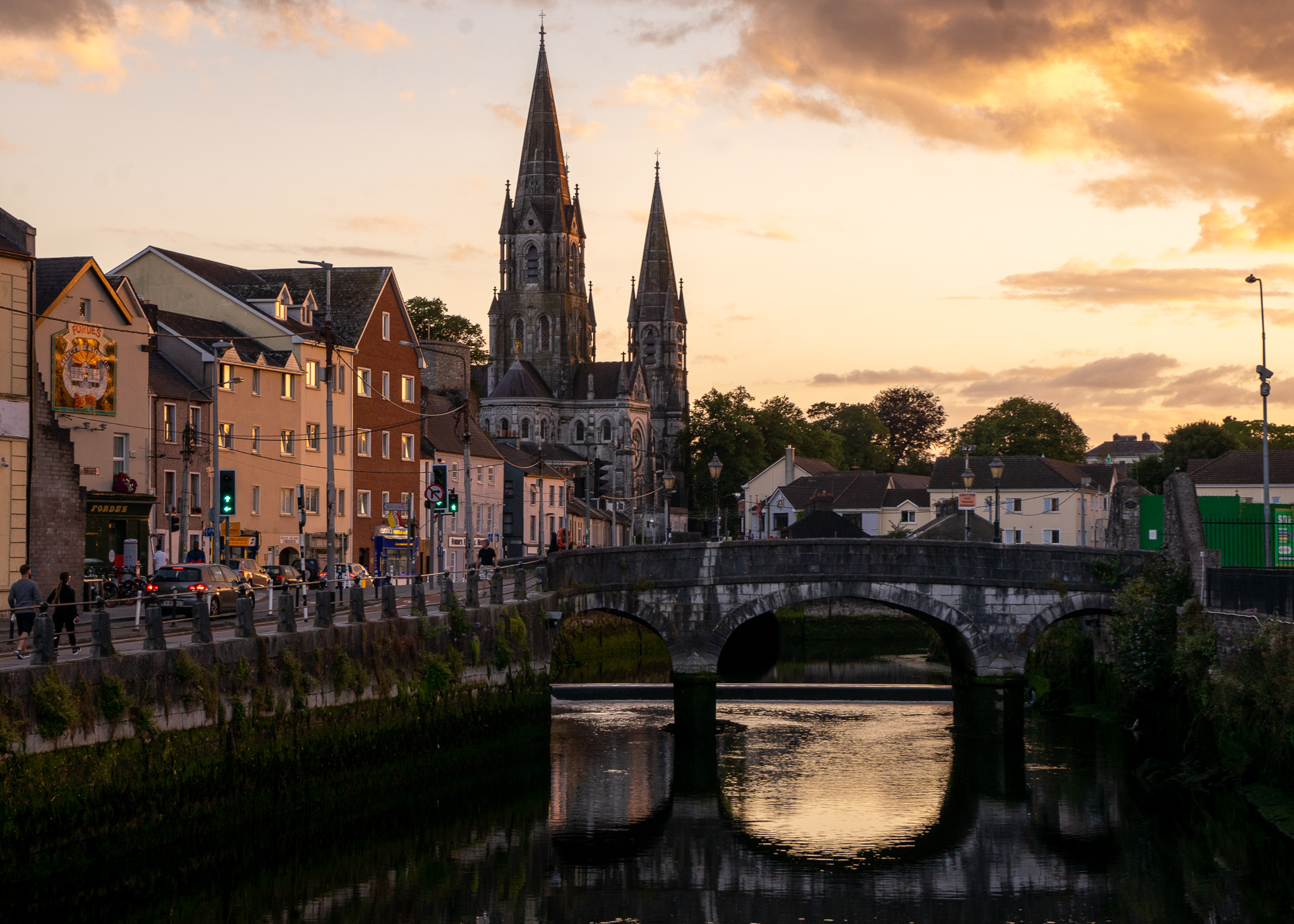a view of cork, ireland at sunset with the church towers and stone bridge 
