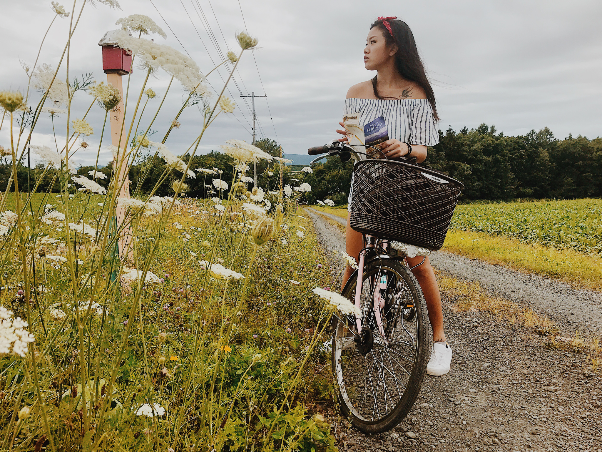 A girl holding a map on a bicycle in Biei in Hokkaido in summer