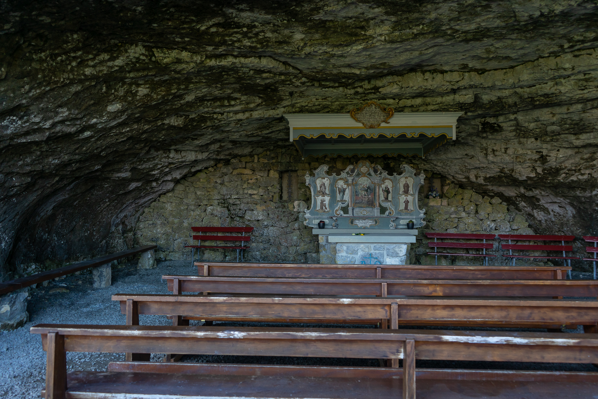 A small chapel with wooden benches inside a cave