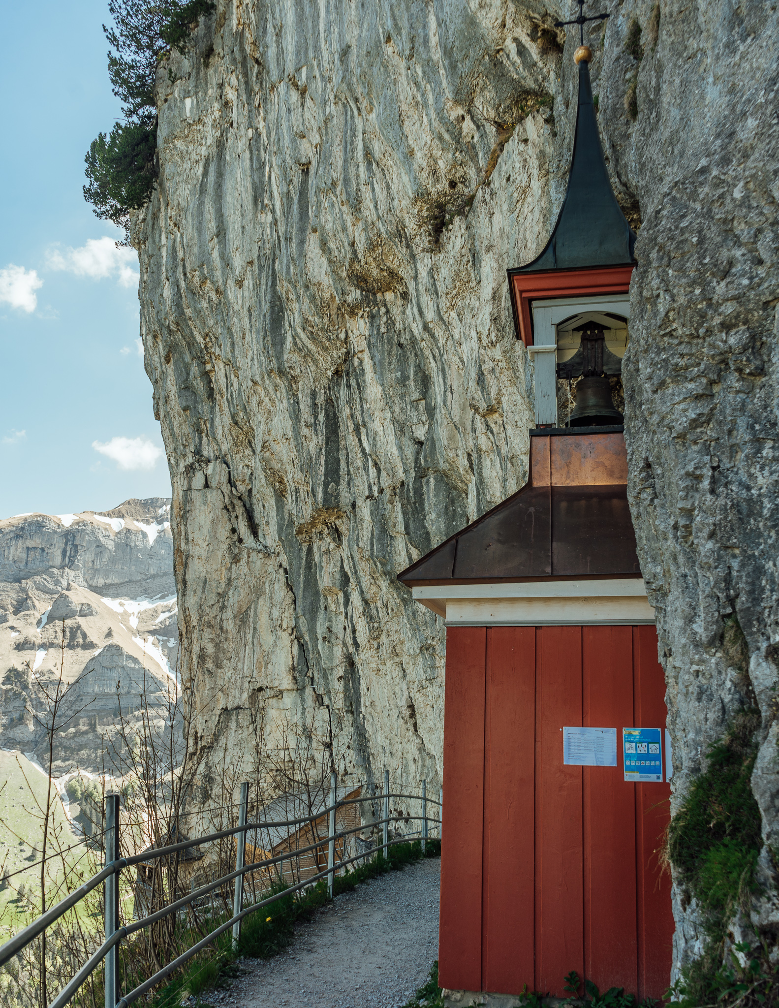 An old red, wooden chapel next to a cliff
