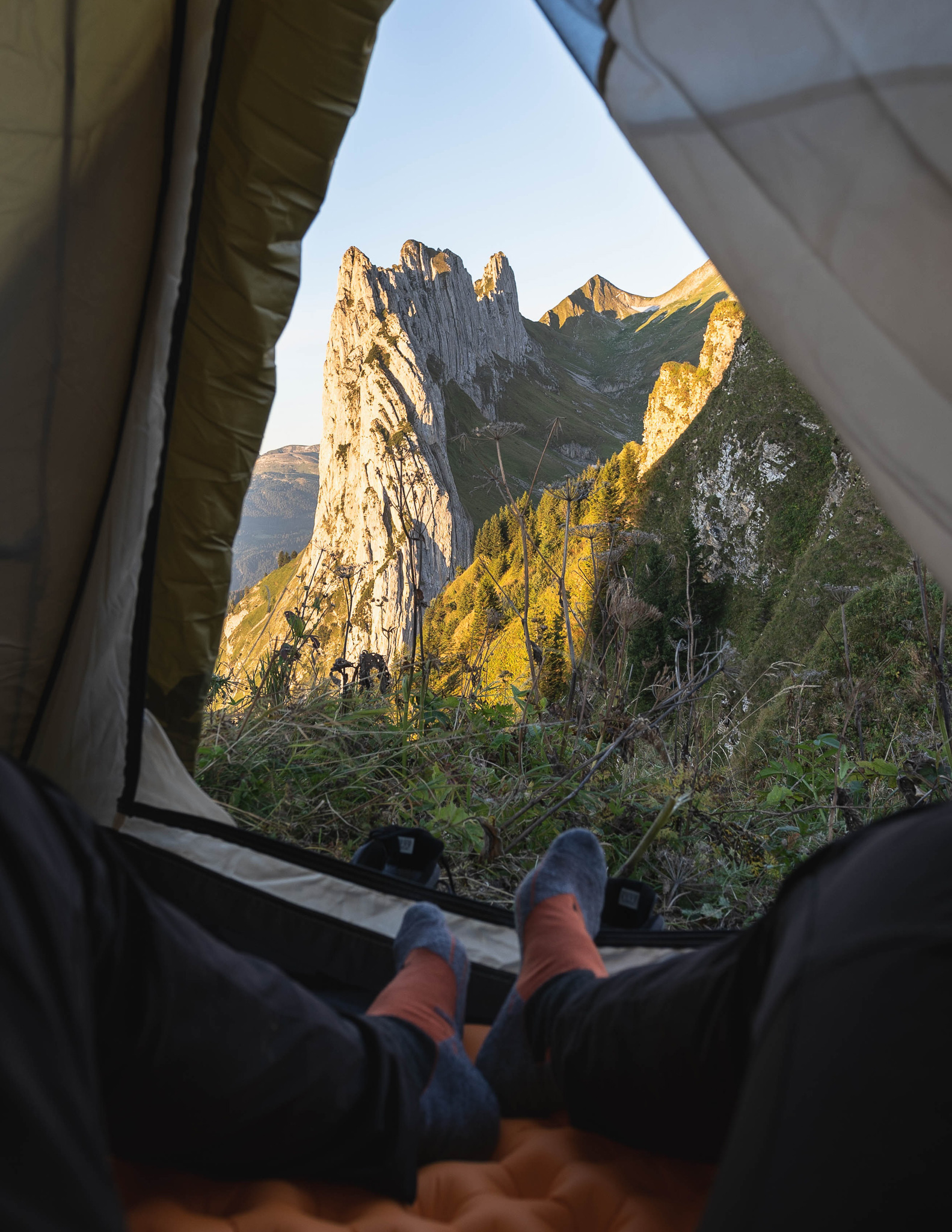 a person sticking their feet out of a tent overlooking mountains