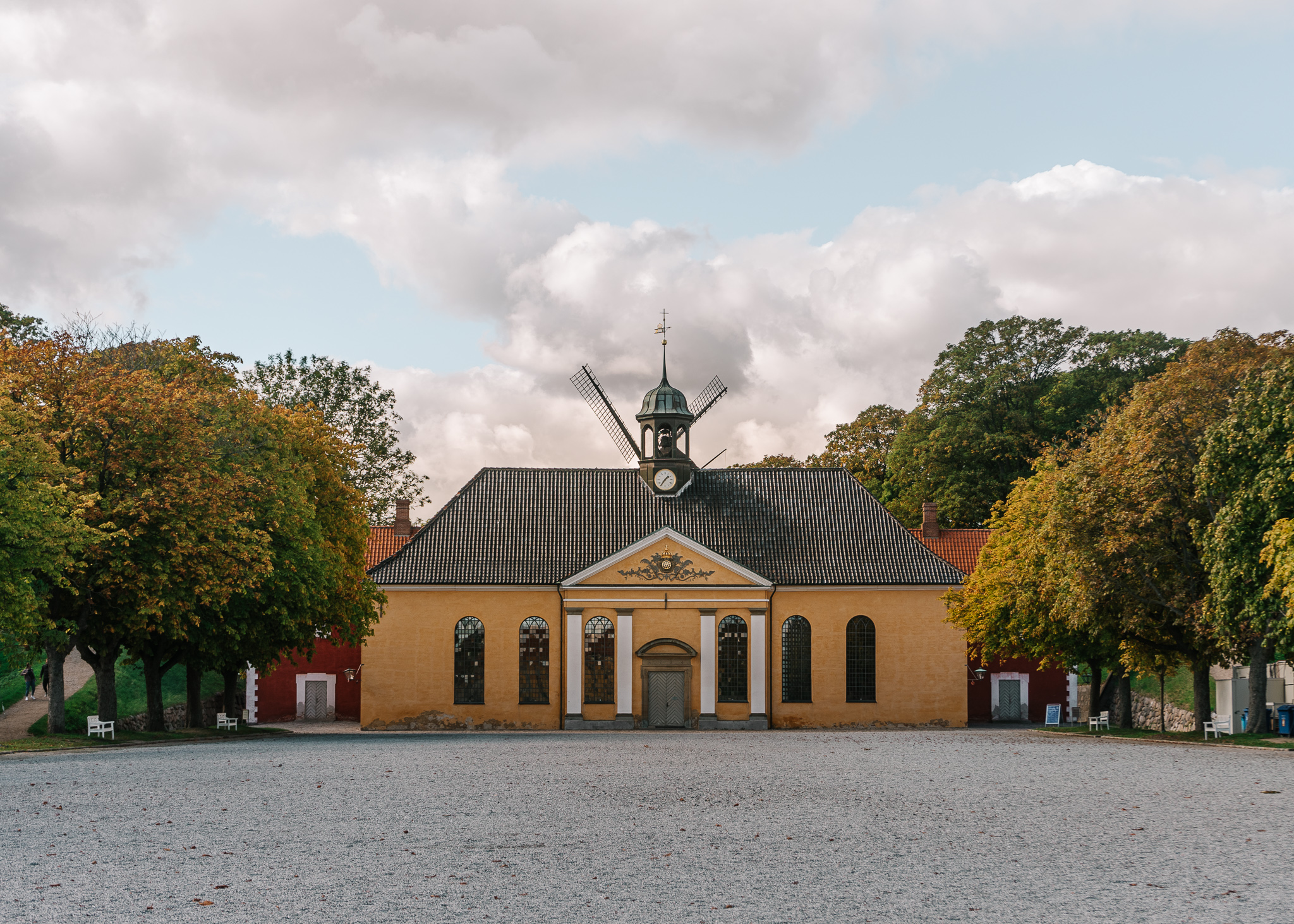 A yellow building with trees on each side in a deserted lot area in Kastellet, Copenhagen.