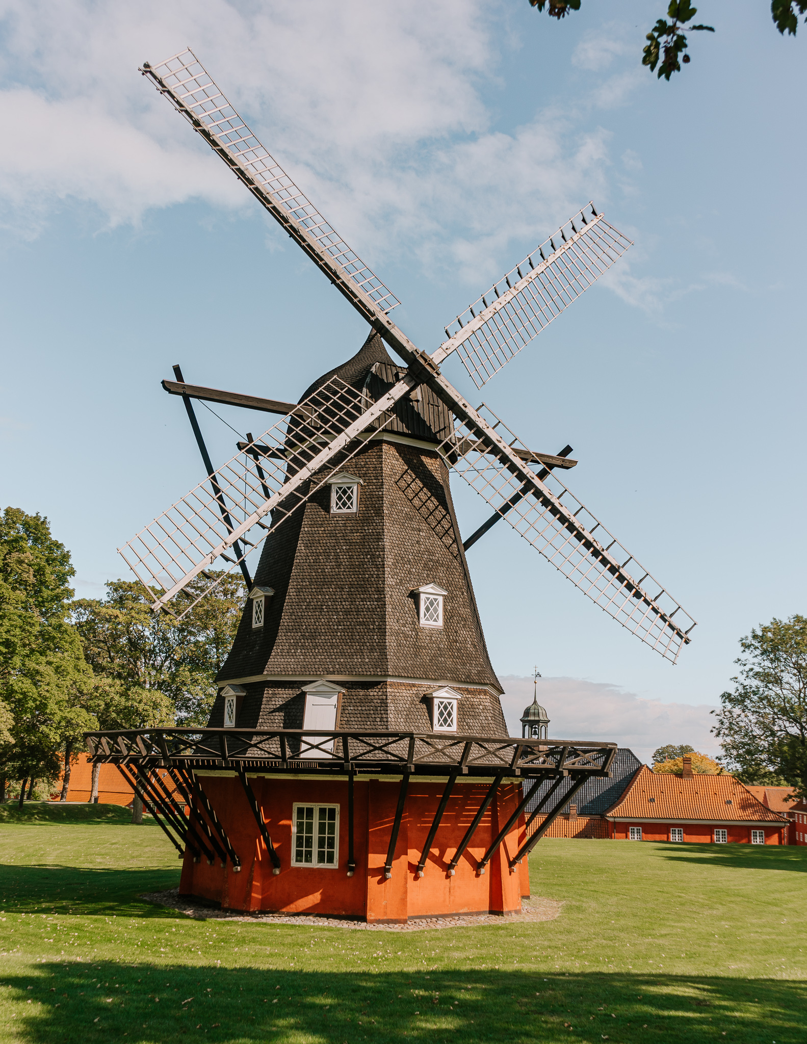 A black and red historic looking windmill in a grassy park on a sunny day in Kastellet, Copenhagen.