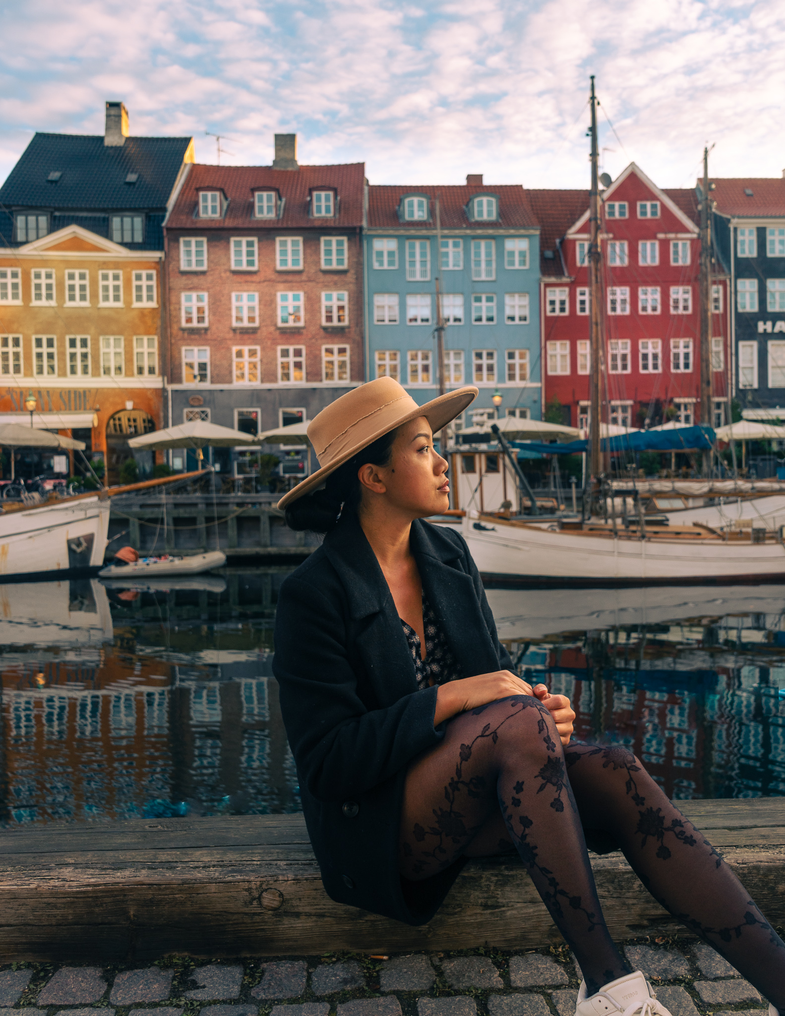 a woman sitting in front of the colorful fisherman houses in Nyhavn during 2 days in Copenhagen