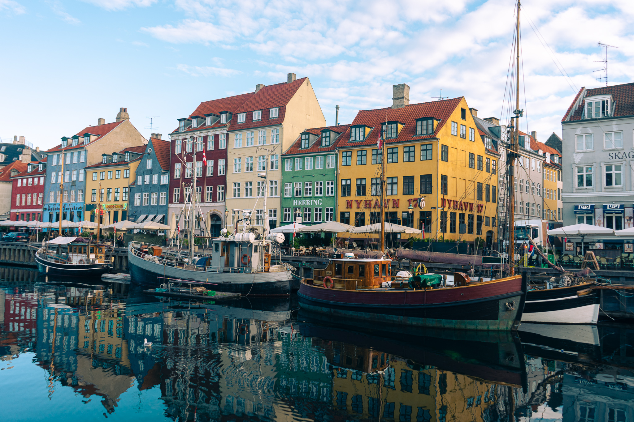 Historic yellow, green, blue and red fishermen houses line the canal at sunrise in Copenhagen