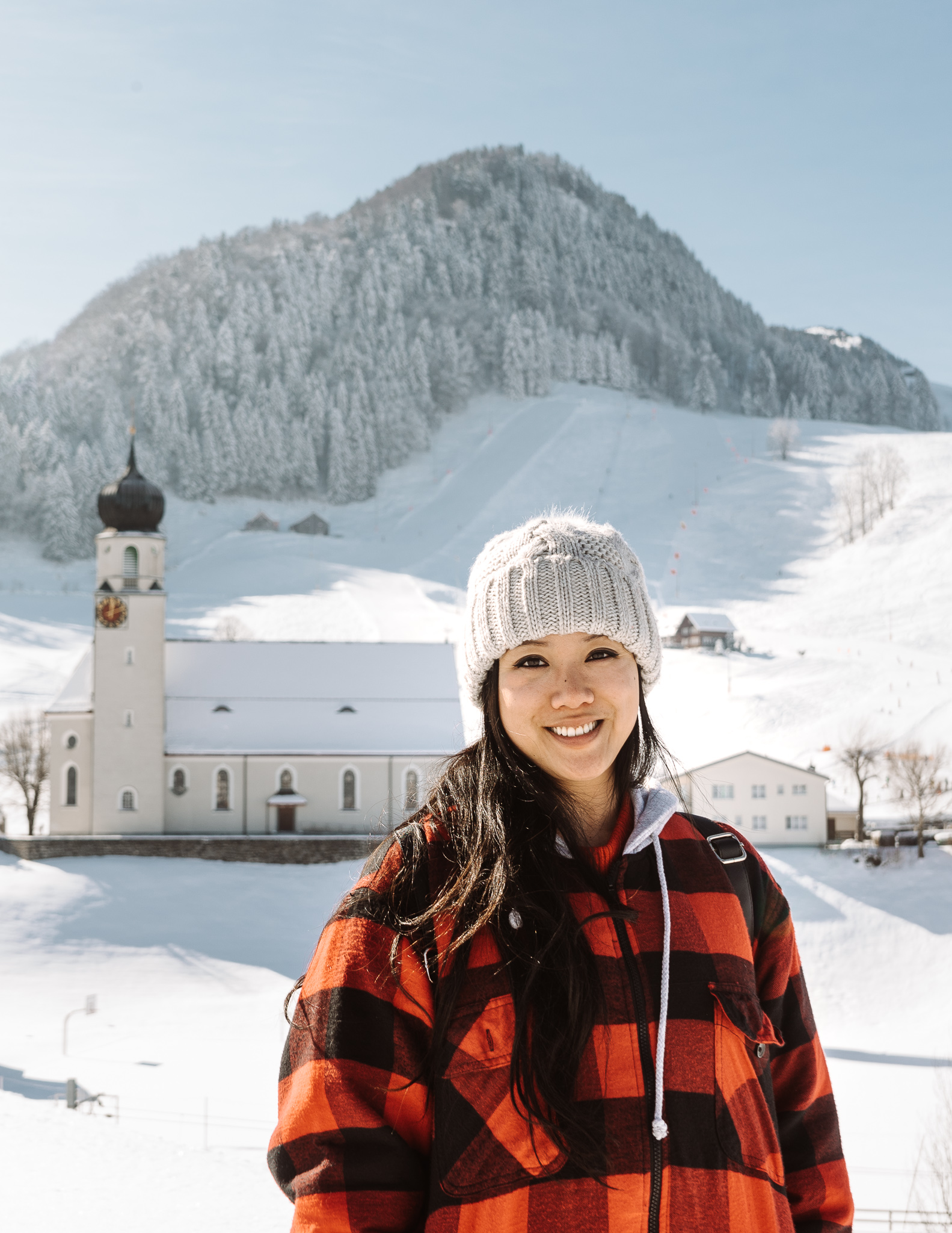 woman in front of a snowy mountain and church on a sunny day in Appenzell