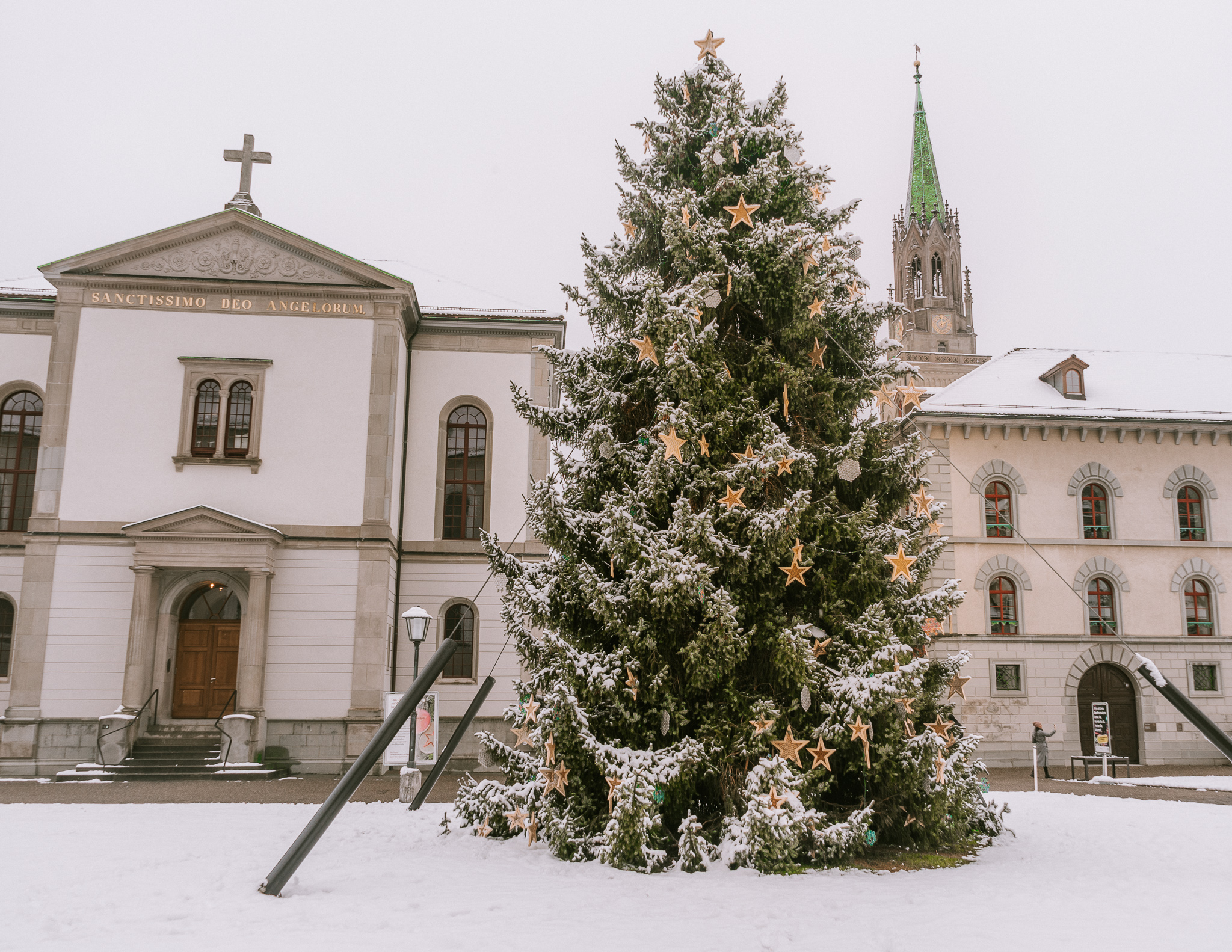 A Christmas tree in front of St. Gallen cathedral in the snow during the day time