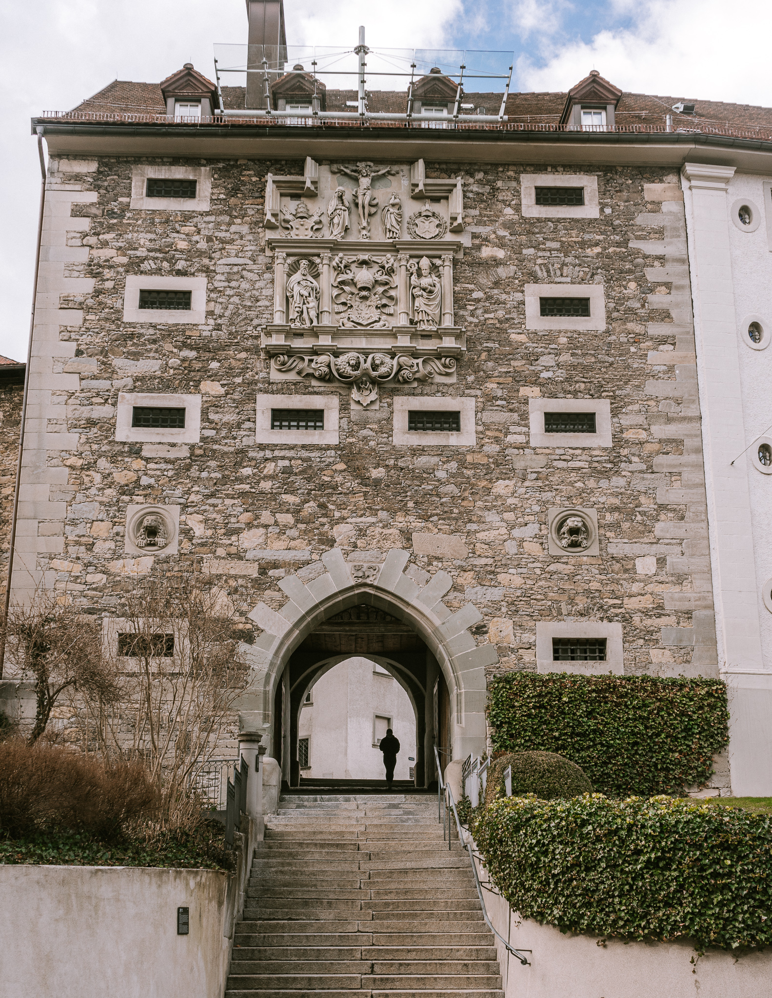 The Karlstor Gate, or the Gate of St. Charles in St. Gallen; a large medieval stone gate with stairs leading through it.