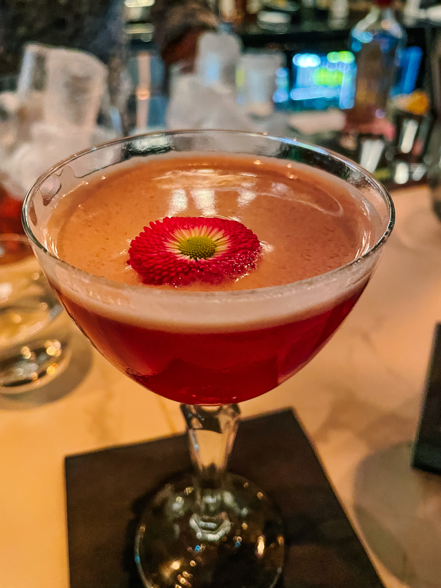 a pink cocktail with a pink flower as a garnish, in a glass at Magnum Wine Bar in St. Gallen