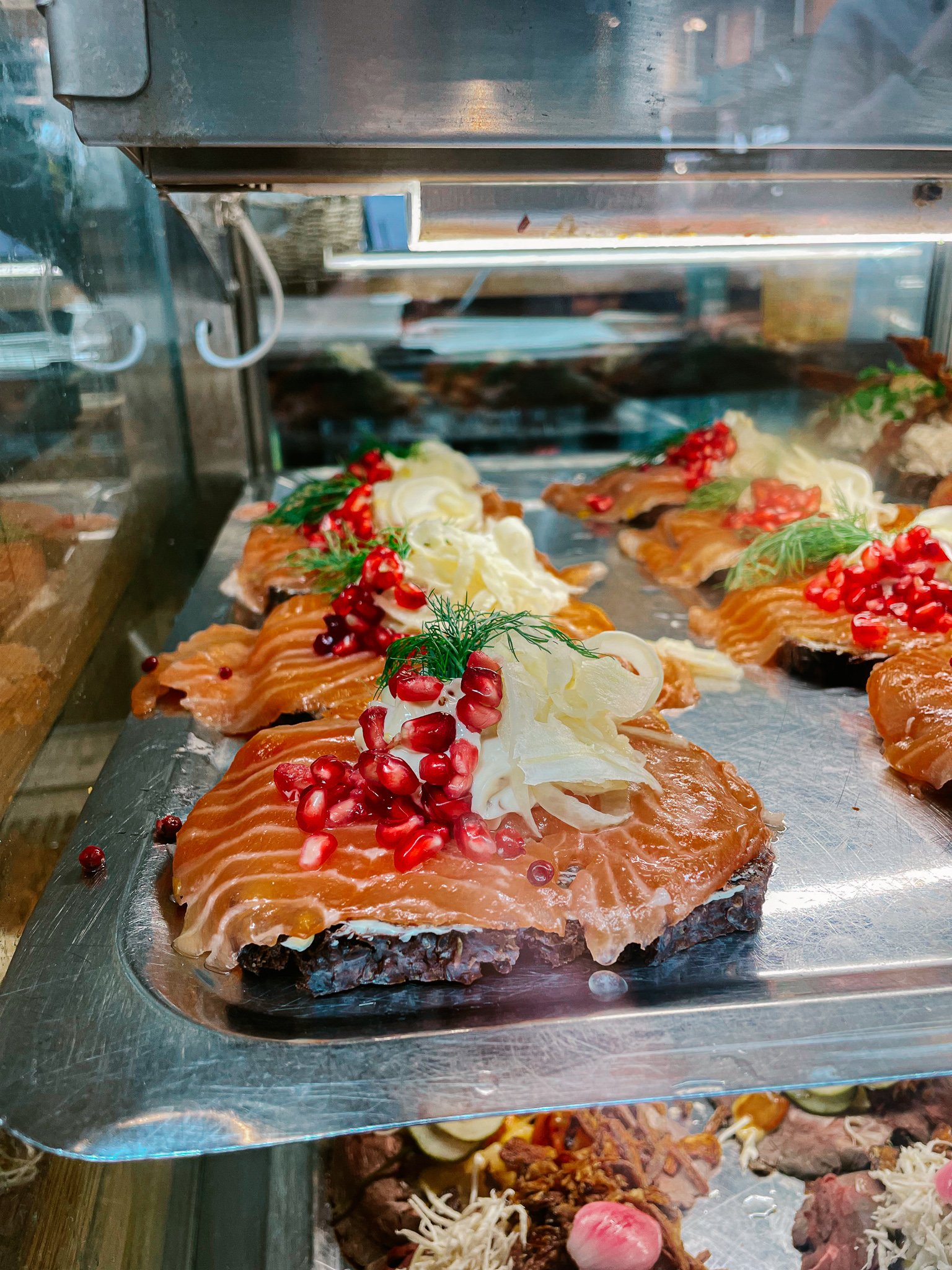 An open faced sandwich called Smorrebrod, with salmon, pomegranite seeds and ginger on top on a steel tray in Tovehallerne in Copenhagen.