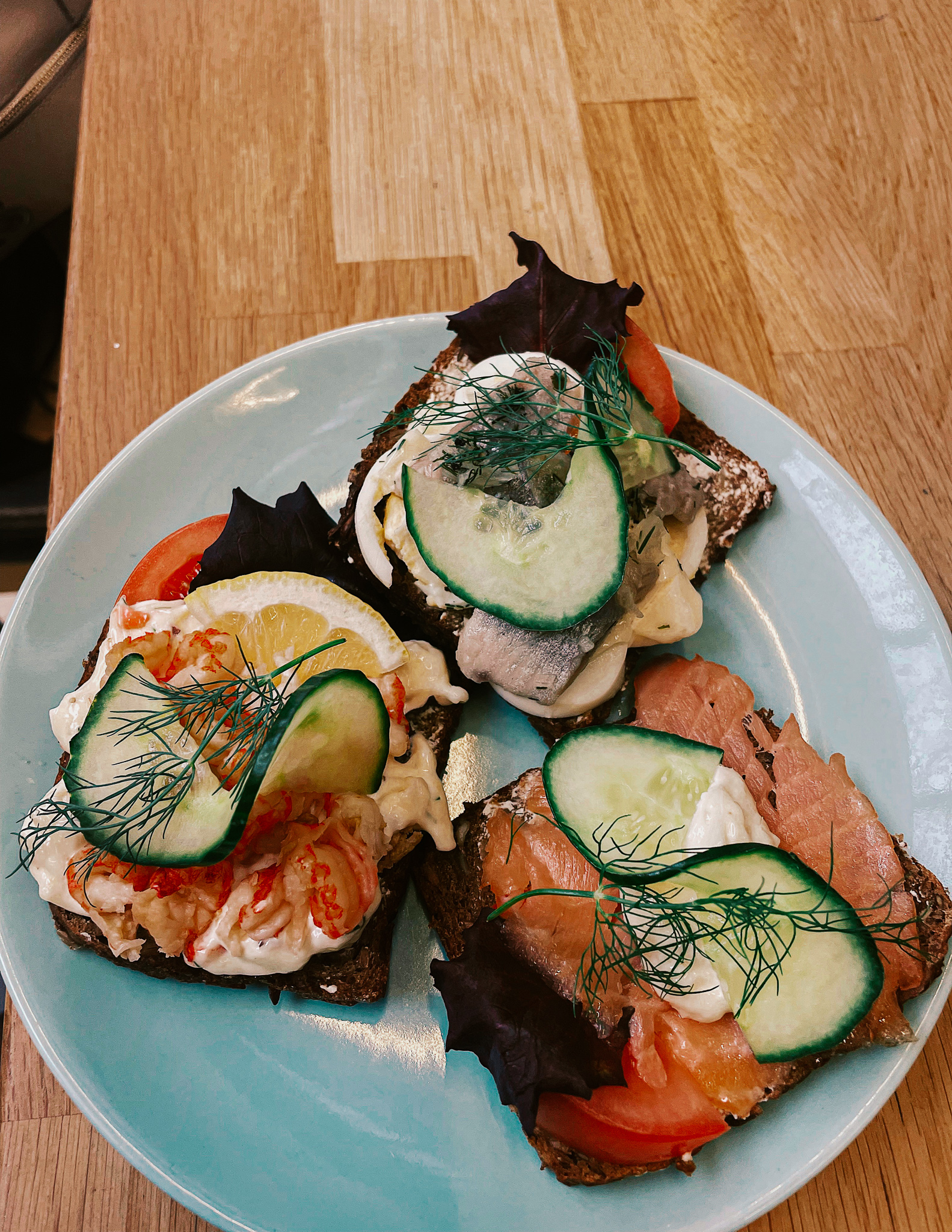 3 Smørrebrød in Copenhagen, open faced sandwiches on Danish rye bread, with lobster, salmon and herring on top with herbs and mayonnaise. 