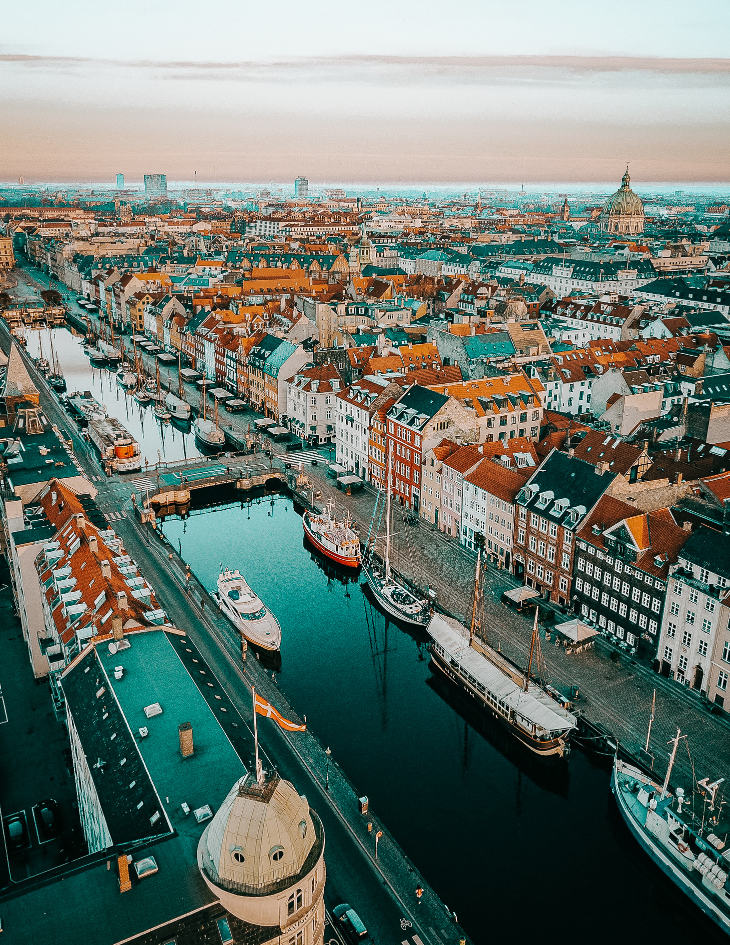 A view of Copenhagen from above, with a view of the Marble church in the distance and the fisherman houses of Nyhavn and the canal below.