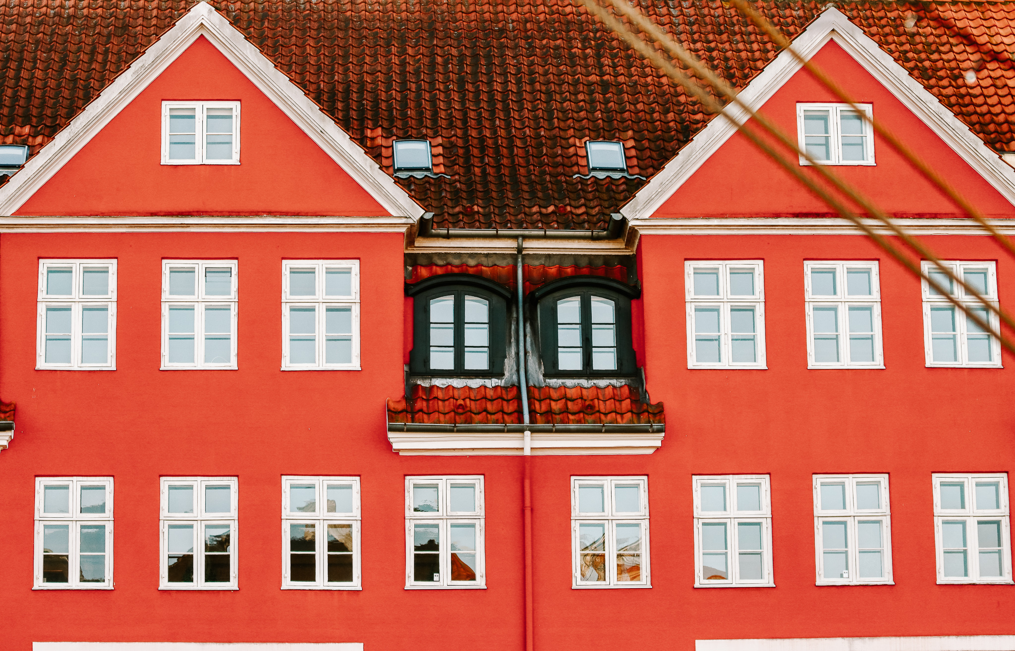 a close up a red fisherman's house in Copenhagen, with many white windows and a tiled roof.
