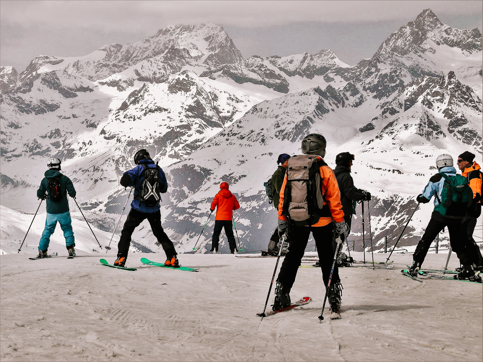 8 skiiers standing around at a ski run in the alps during winter.