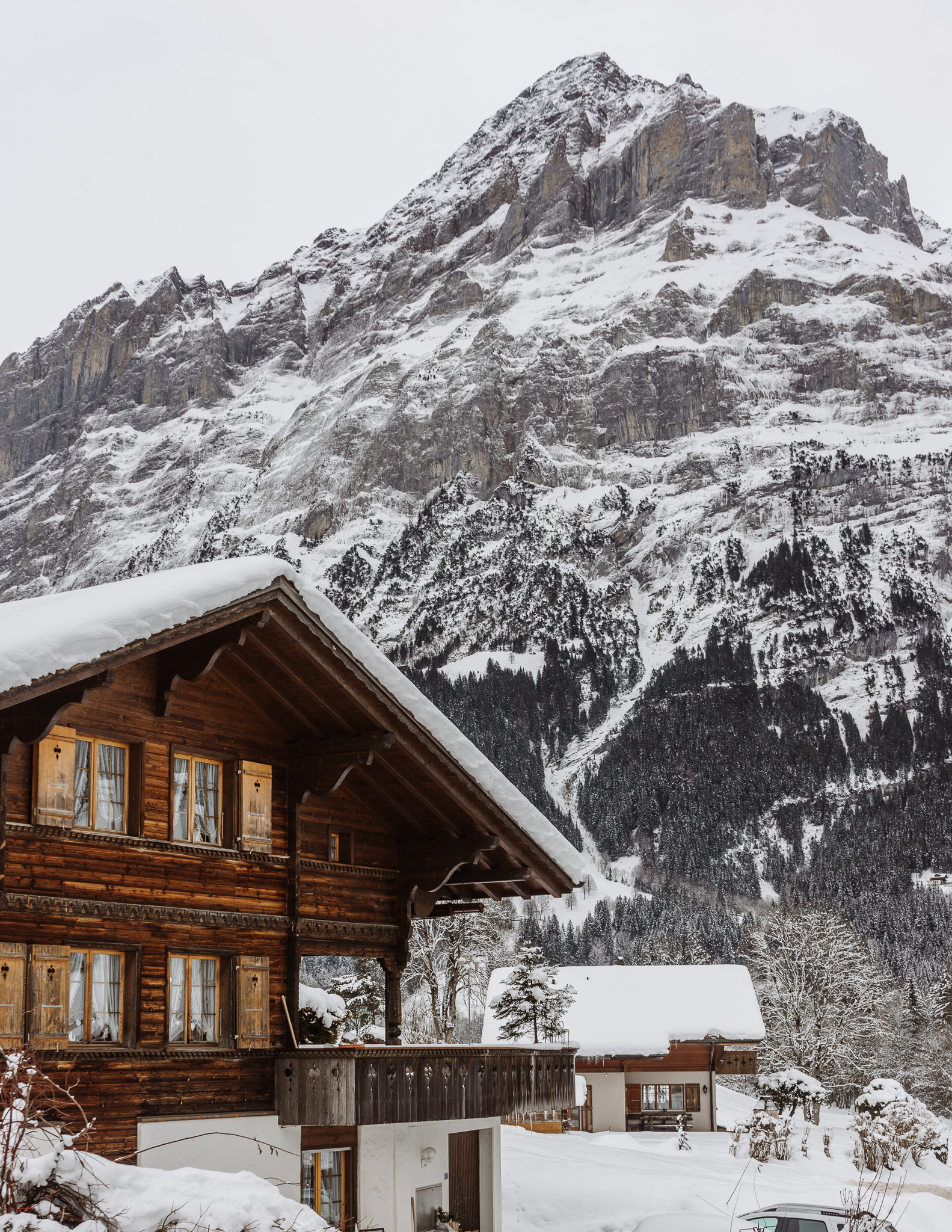A view of a snowy mountain and a wooden house in Grindelwald village, near Lauterbrunnen in winter.