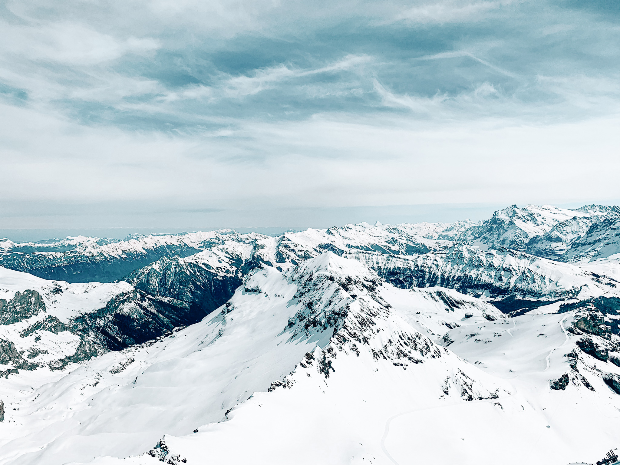 A view of many mountains in the Swiss Alps as viewed from Mount Schilthorn ski resort on a winter day.