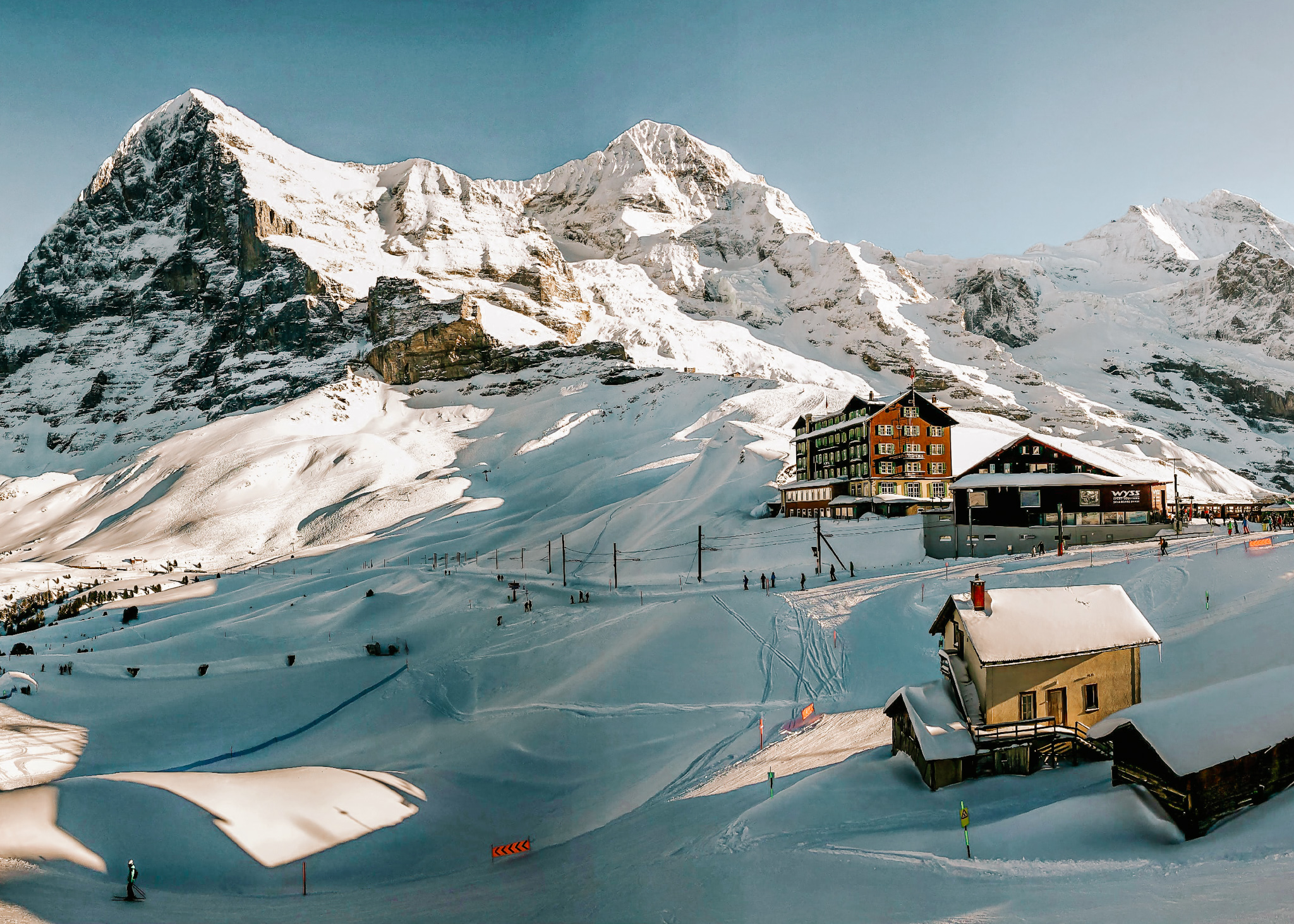 A high altitude Swiss ski resort near Lauterbrunnen in winter, with lots of snowand people snowboarding.