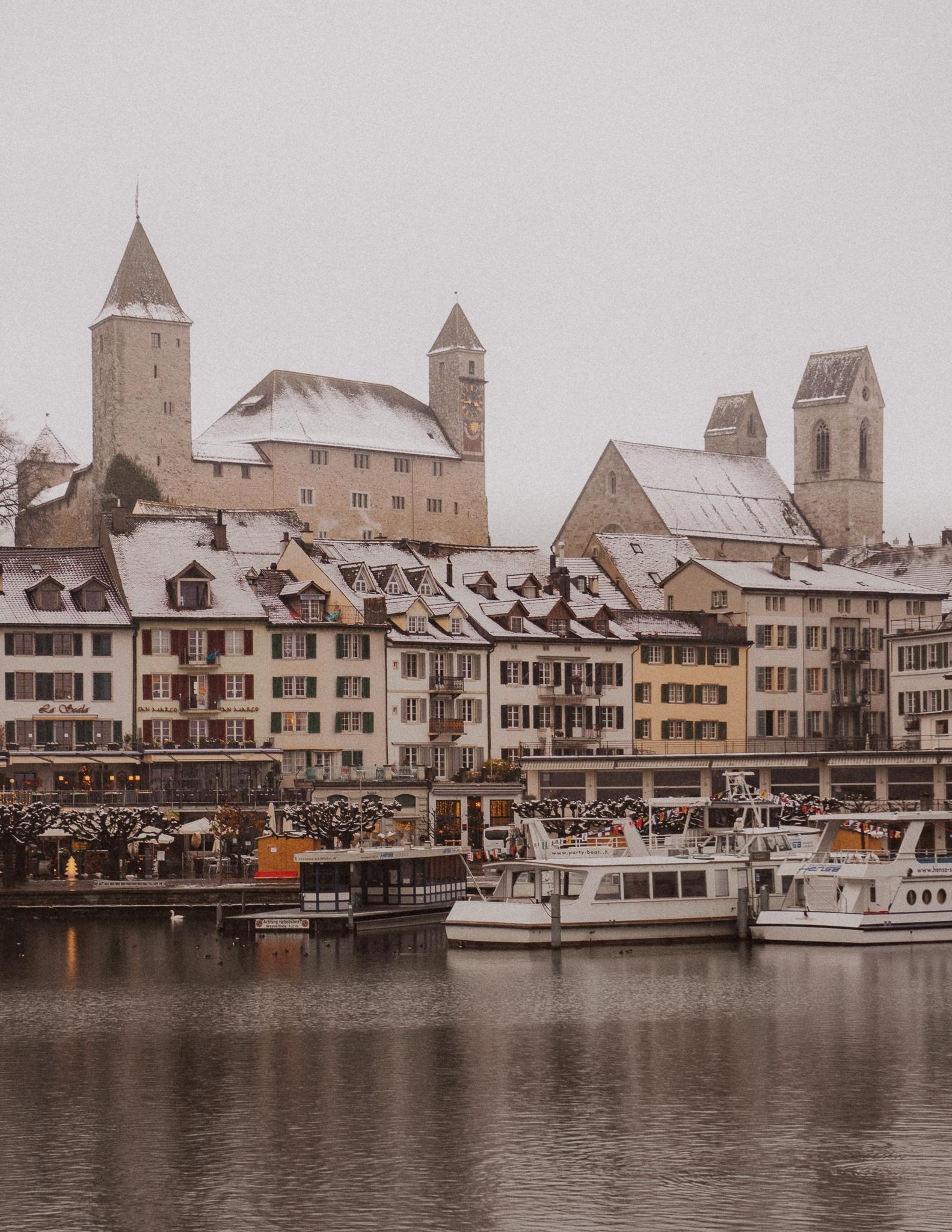 Rapperswil castle and the town below it on a snowy winters day with the lake in front of it.
