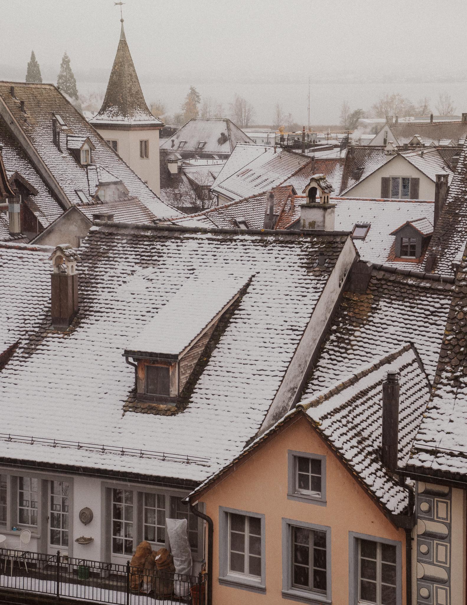View of snow capped roofs in Rapperswil  from Rapperswil Castle Park on a foggy day.