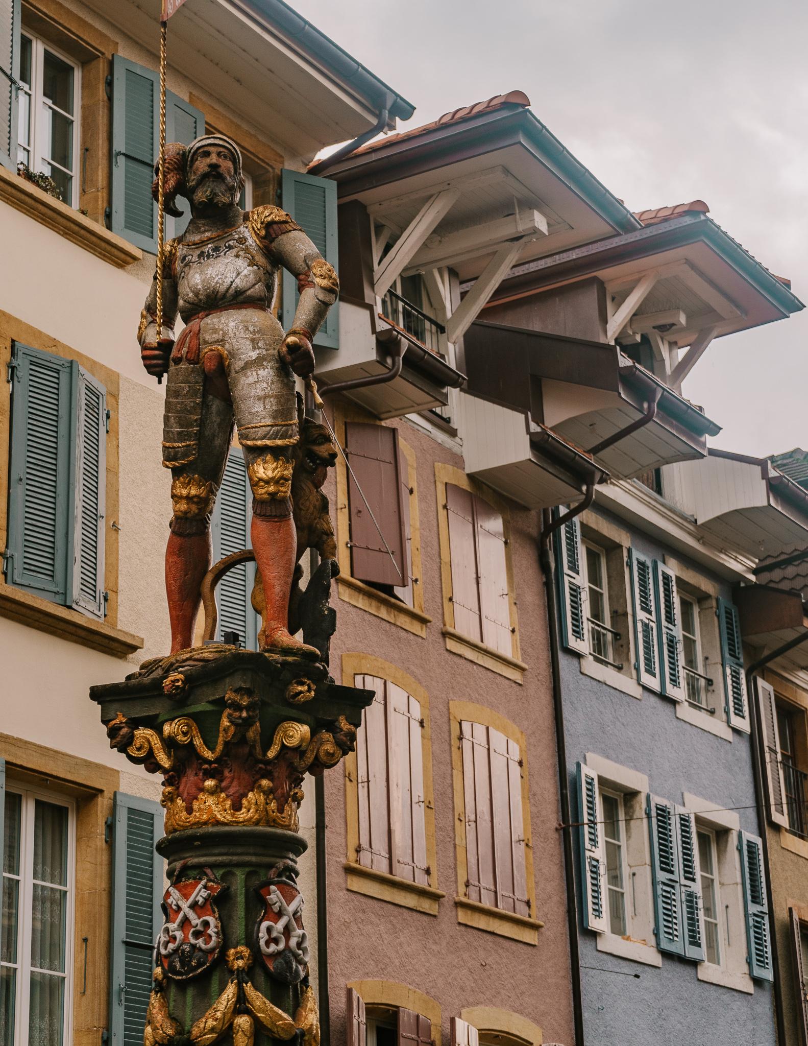 a painted statue on a tall wooden pole in the village of La Nueveville, Switzerland