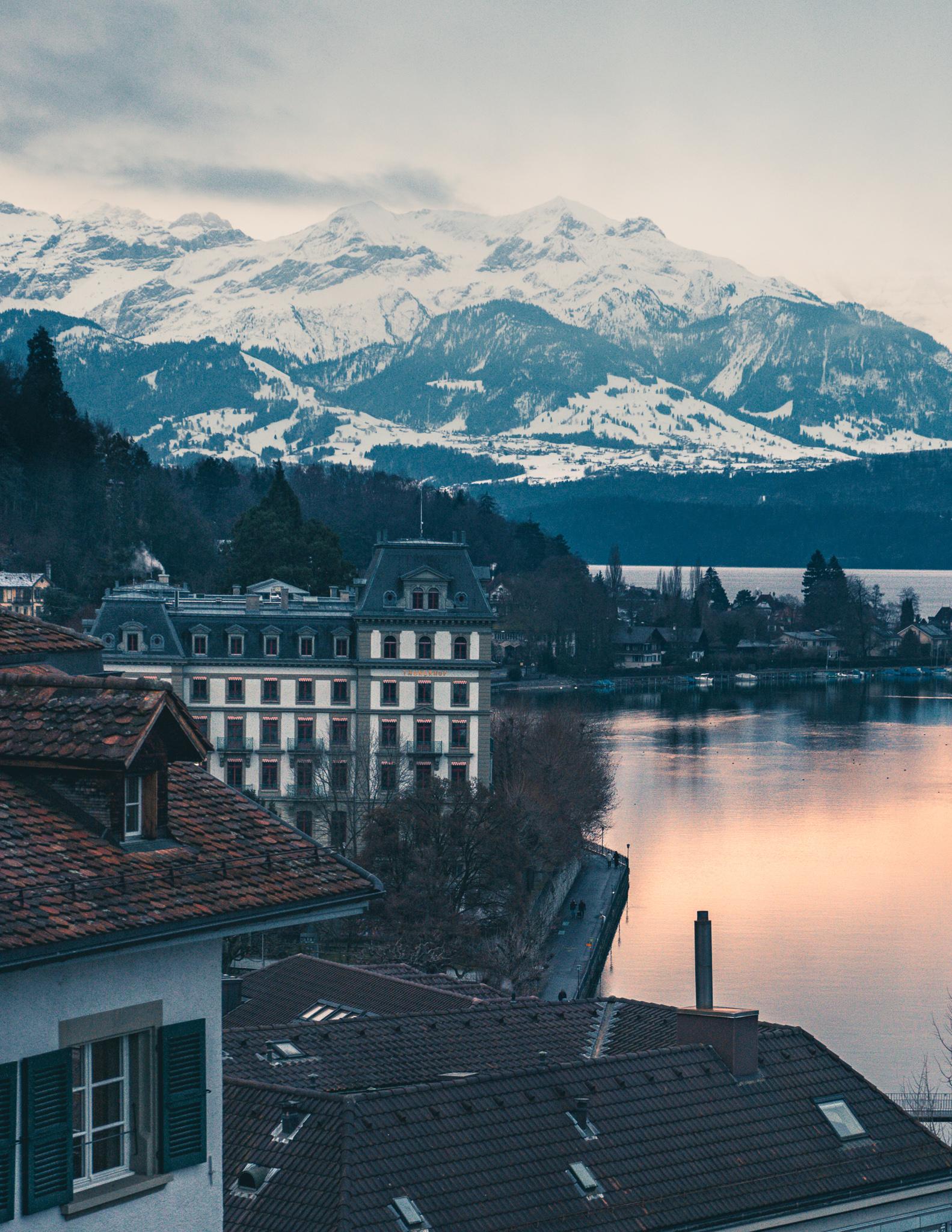 A hotel next to Thun lake in front of Swiss mountains covered in snow