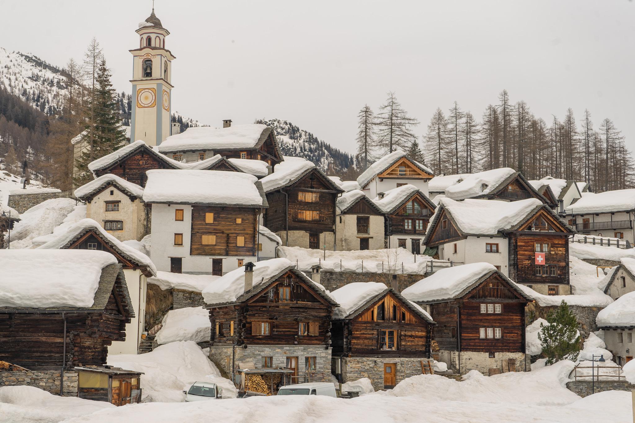 Bosco Gurin village with a lot of snow on all the wooden houses roofs and one tall church clock tower