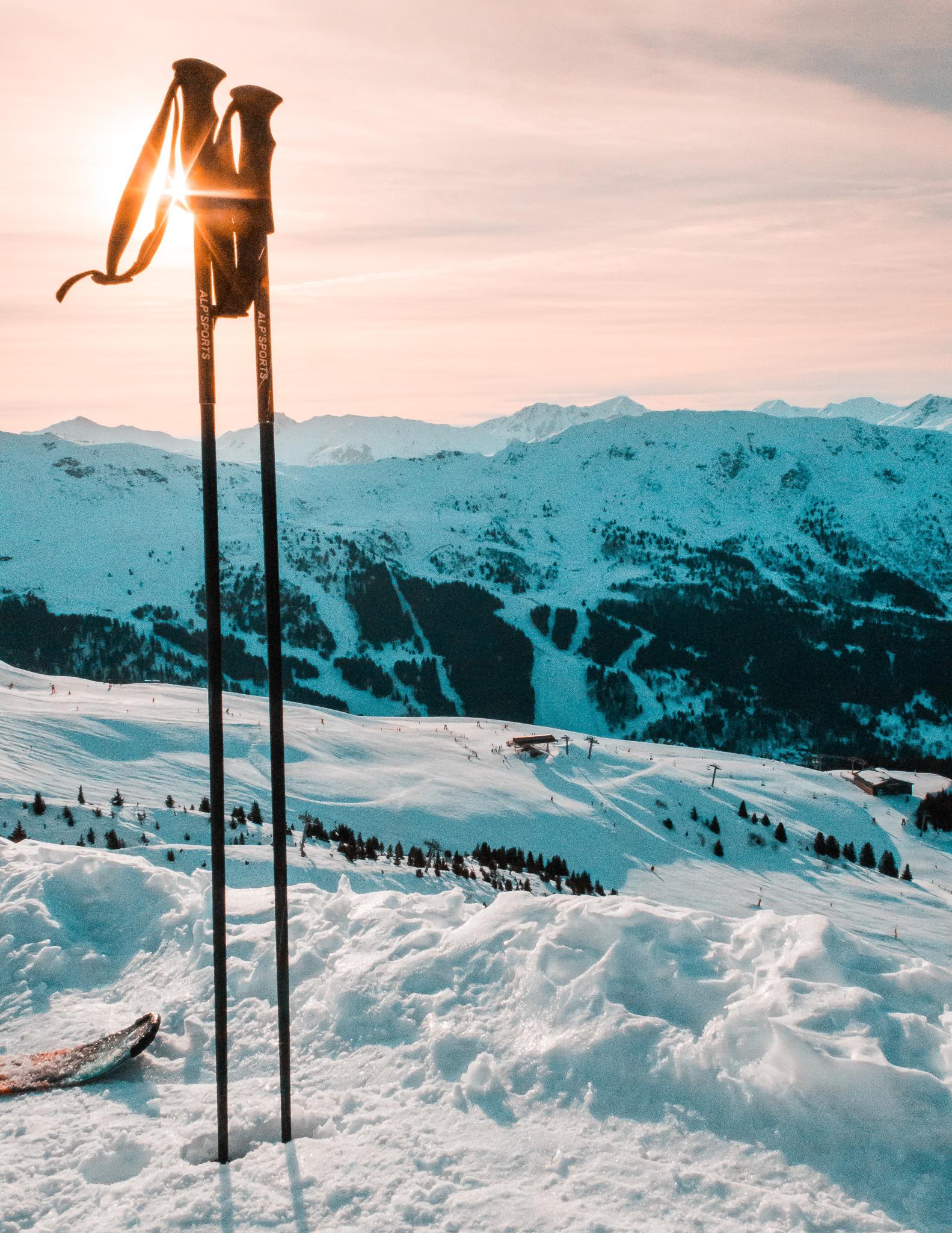 ski poles dug into the snow on a snowy mountain on a sunny day