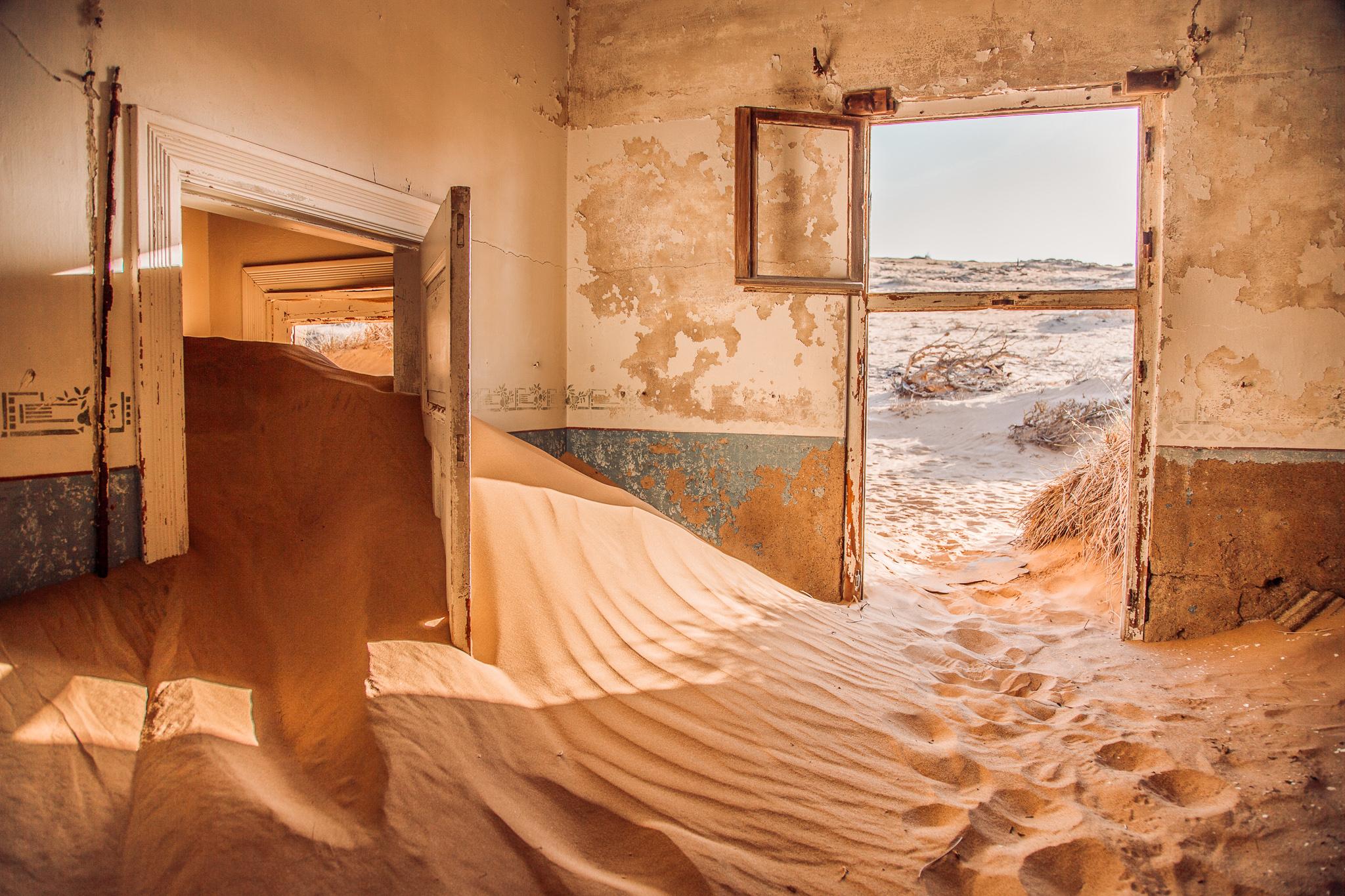 an abandoned rusty building filled with red sand from the desert