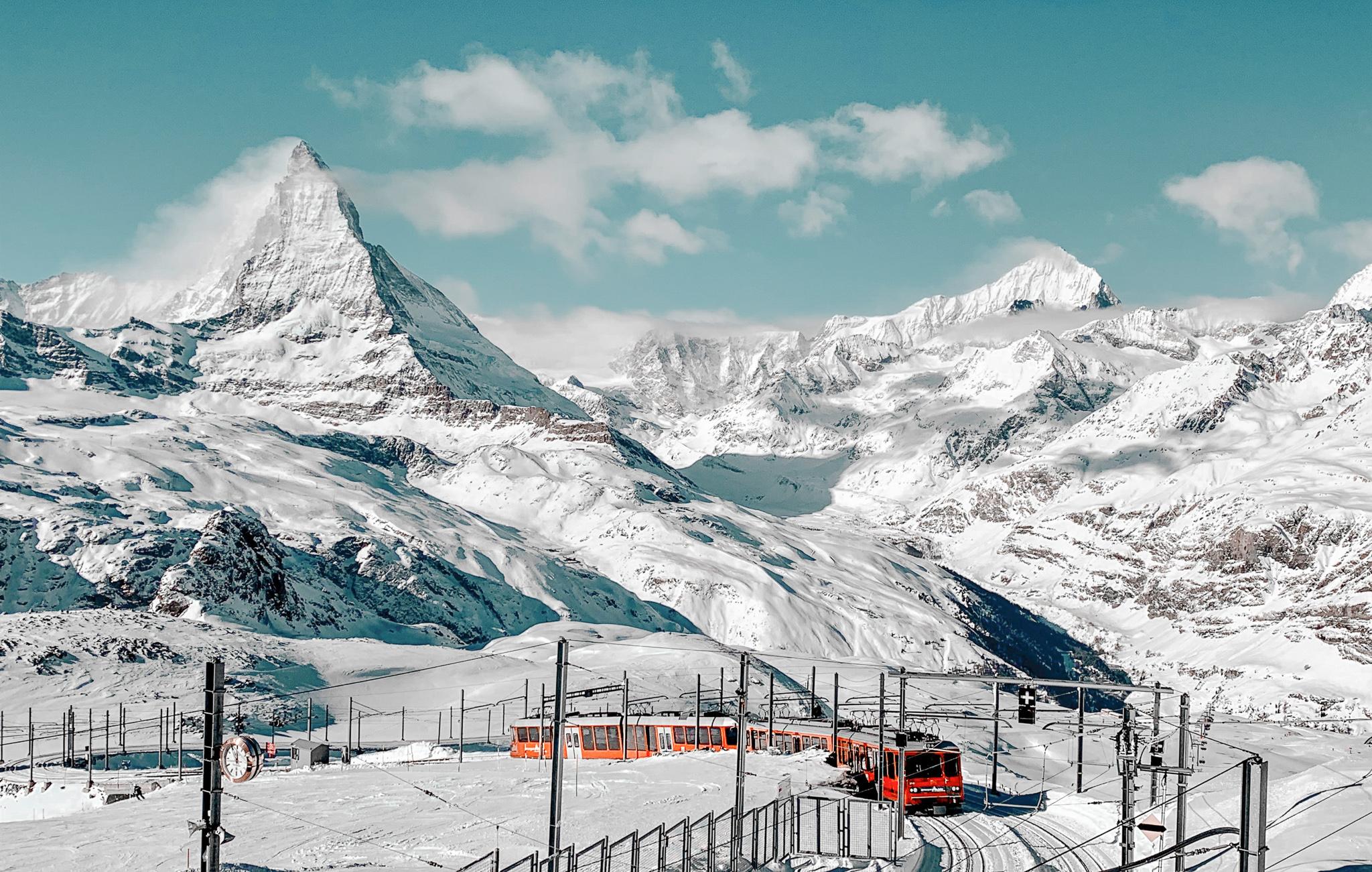 Matterhorn covered in snow and a train station in front on a clear sunny winter day