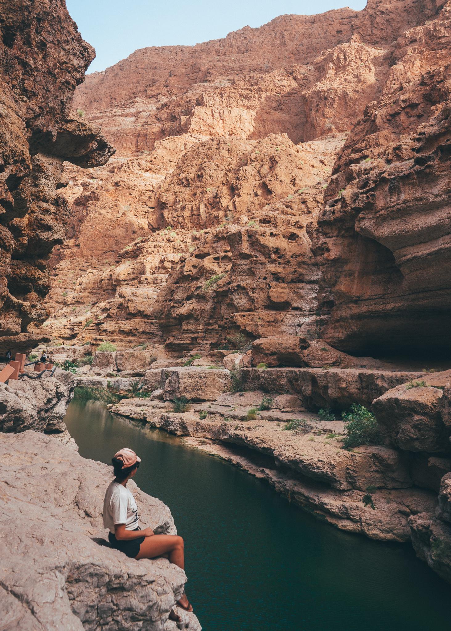 A girl sitting on a rocky ledge in Wadi Shab in Oman