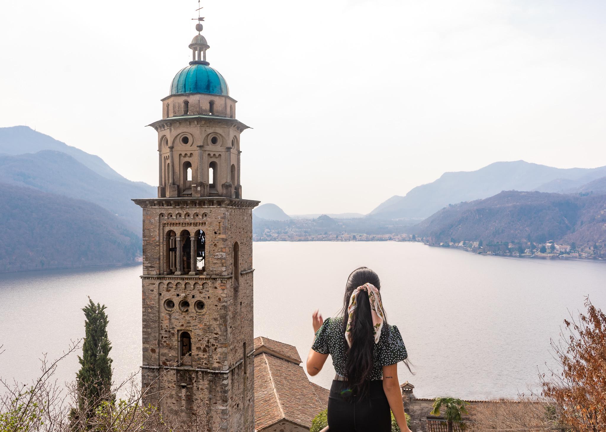 Girl in front of a church tower overlooking Lake Lugano in Morcote village in Ticino, Switzerland