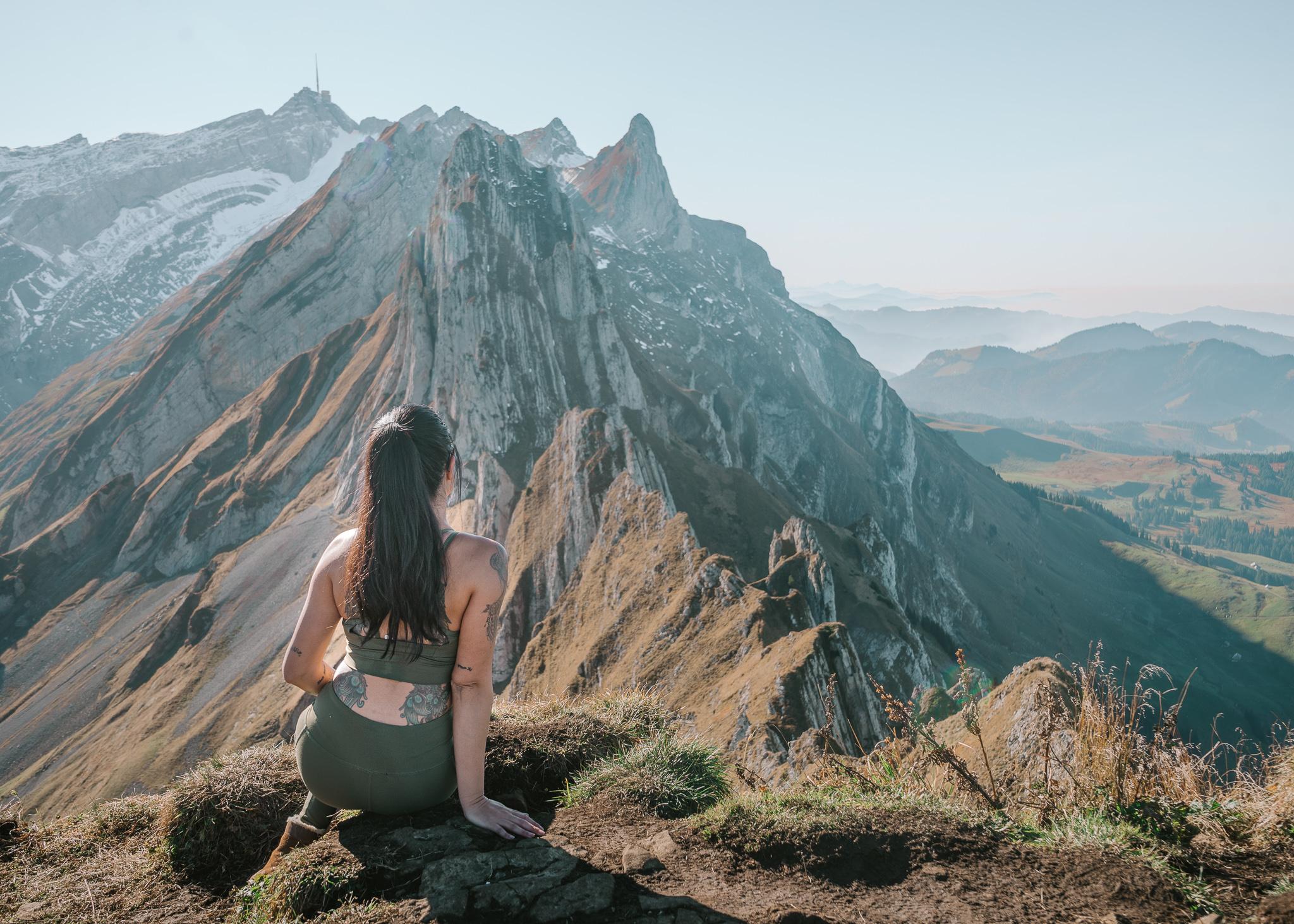 A girl sitting on the ground in front of the Shafler mountain ridge in switzerland