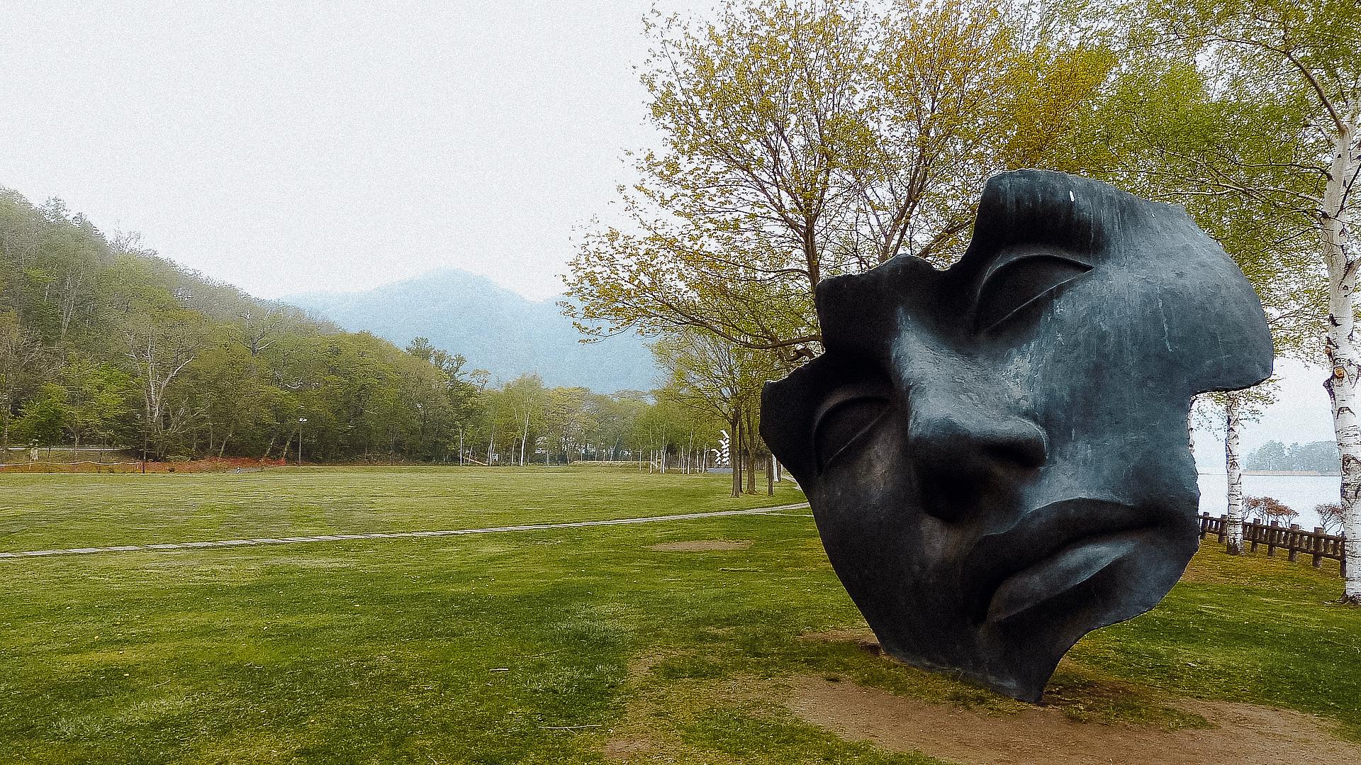 A scultpure of a giant face in a park next to Toya lake in Hokkaido in summer